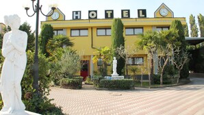 Un edificio amarillo con la palabra "HOTEL" en la fachada, un reloj y una estatua al frente.