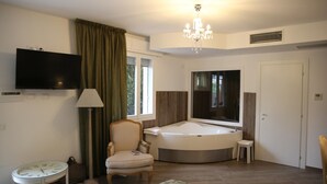 Un baño moderno con bañera, tocador, televisor y candelabro.