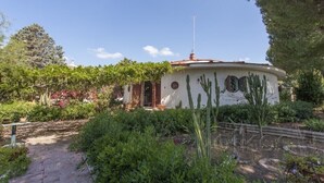 Un bâtiment circulaire surmonté d’un toit rouge, entouré d’une végétation luxuriante et de cactus.