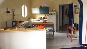 Une cuisine compacte avec des carreaux de sol jaunes à motifs, un four à micro-ondes, un réfrigérateur et un coin repas comprenant une table et des chaises.