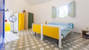 Une chambre à coucher comprenant un lit, un bureau, une chaise, une armoire et un ventilateur.