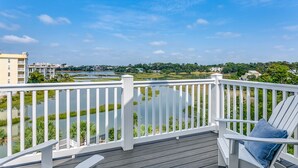 Eine Terrasse mit weißer Geländer, das auf ein Gewässer und Grünflächen blickt.