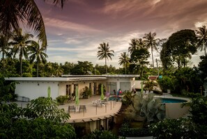 Un resort moderno con piscina, zona de estar al aire libre y exuberante vegetación tropical.