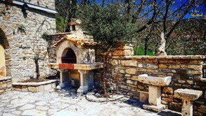 Un patio de piedra con una fuente, una pequeña estructura en arco y una estatua.