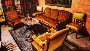 Un salón acogedor con un sofá de cuero, sillones a juego, una mesa de centro y una estantería llena de libros.