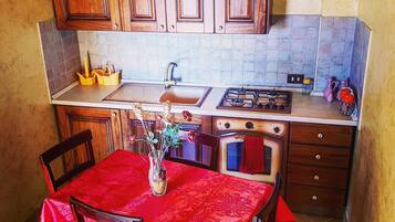 Una cocina compacta con armarios de madera, un lavamanos, una estufa y una mesa de comedor con sillas.