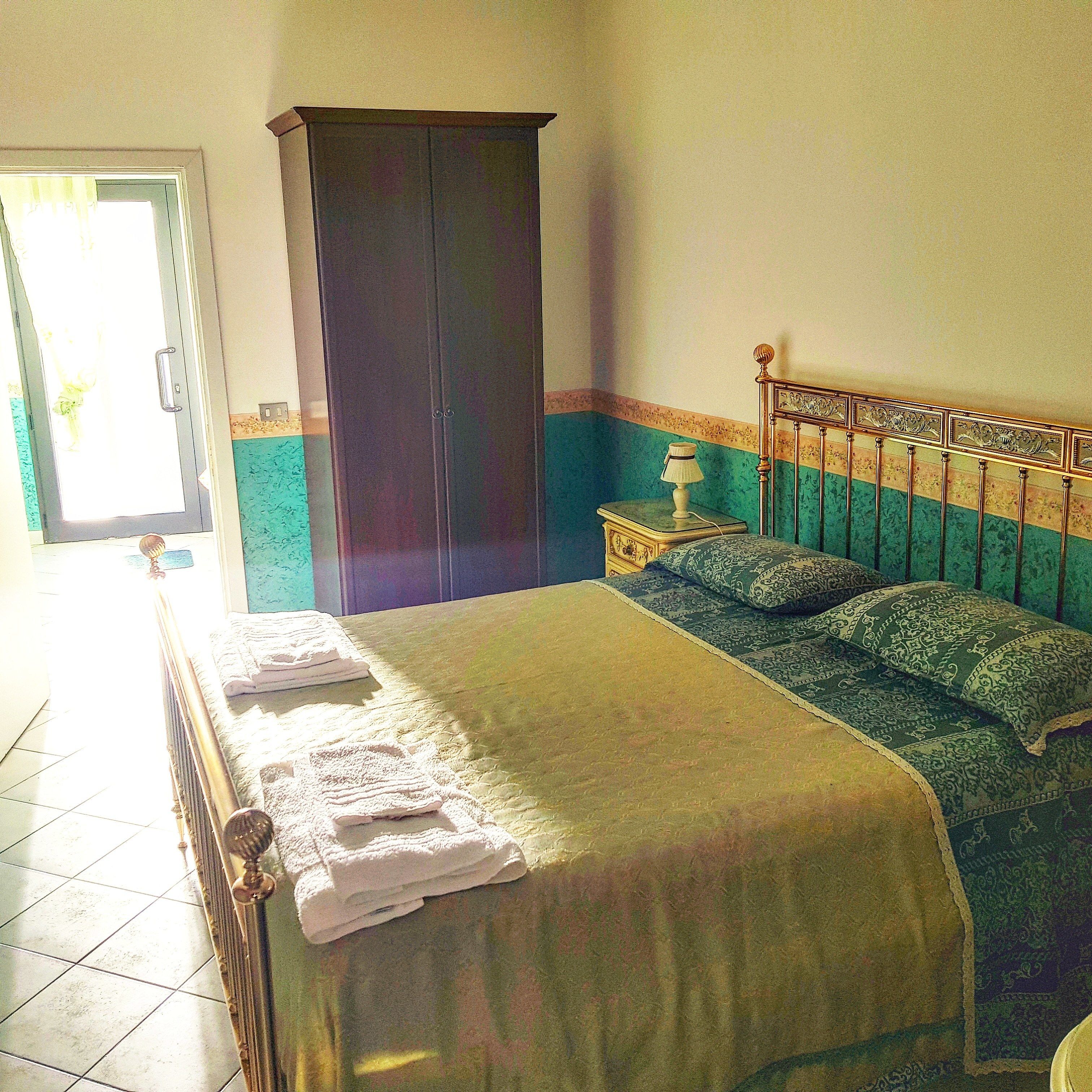 Un dormitorio con cama, armario, mesita de noche y lámpara.