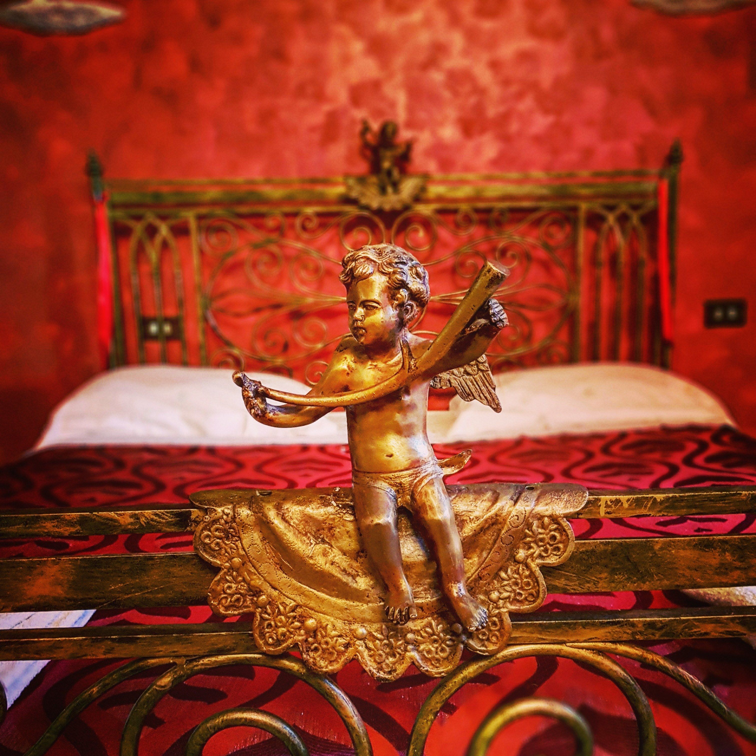 Una cama con una figurita de ángel dorado en el cabecero.