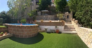 A backyard with a swimming pool, artificial grass, stone walls, and potted plants. - L'Antica Dimora (Macchiagodena)