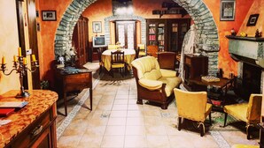 Una sala de estar acogedora con un arco de piedra, una chimenea y una estantería llena de libros.