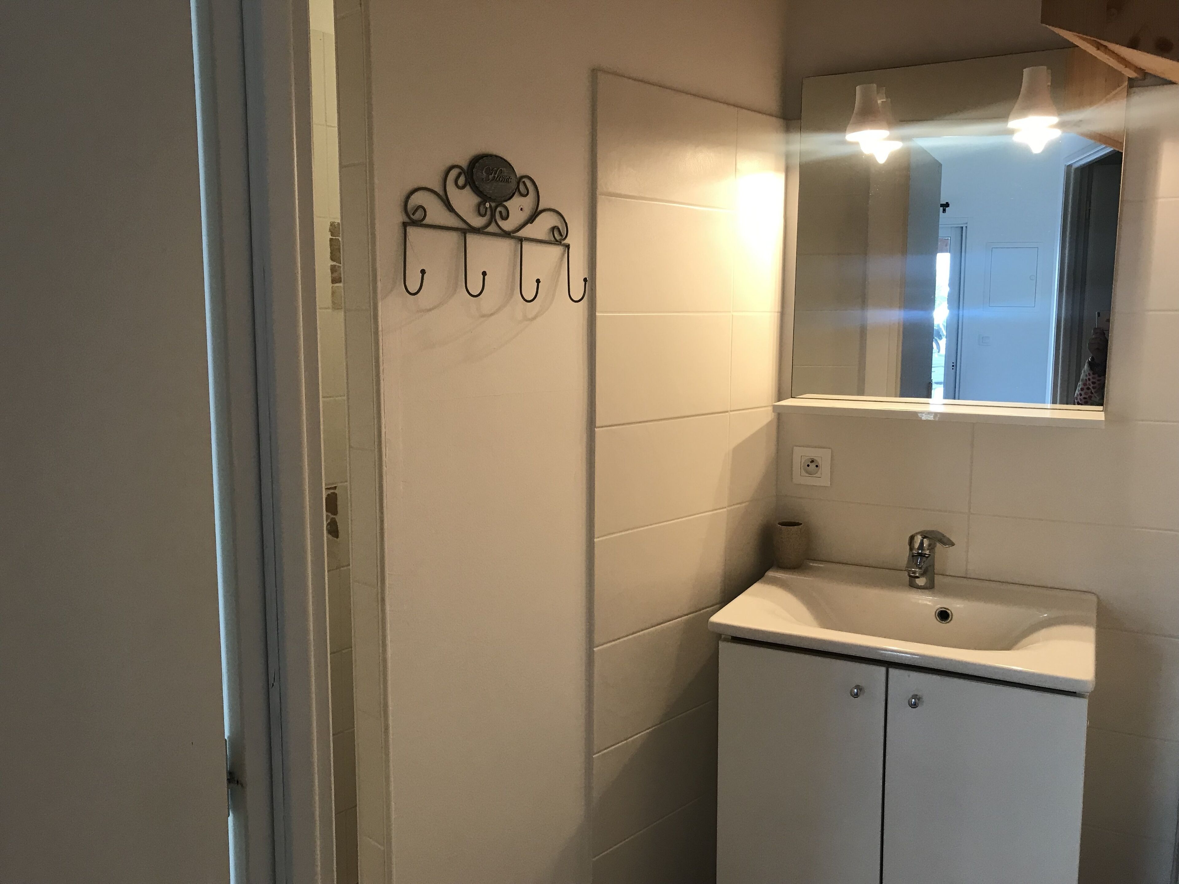 Une salle de bain avec un lavabo blanc, un miroir et un porte-serviettes fixé au mur.