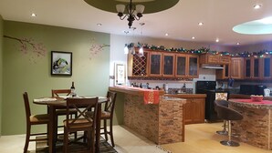 A kitchen with a dining area, wooden cabinets, a brick accent wall, and a chandelier. - A beautiful and safe 3 bedroom home in a gated community (Mausica)