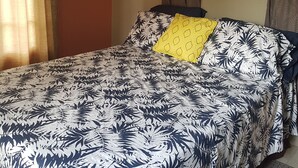 A bed with a leaf-patterned bedspread, a yellow pillow, and a framed landscape painting on the wall. - A beautiful and safe 3 bedroom home in a gated community (Mausica)