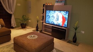 A living room with a flat-screen TV, a sofa, two potted plants, and a decorative vase on a coffee table. - A beautiful and safe 3 bedroom home in a gated community (Mausica)