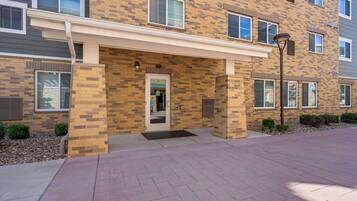 A multi-story residential building with a brick facade, a covered entrance, and a paved driveway.