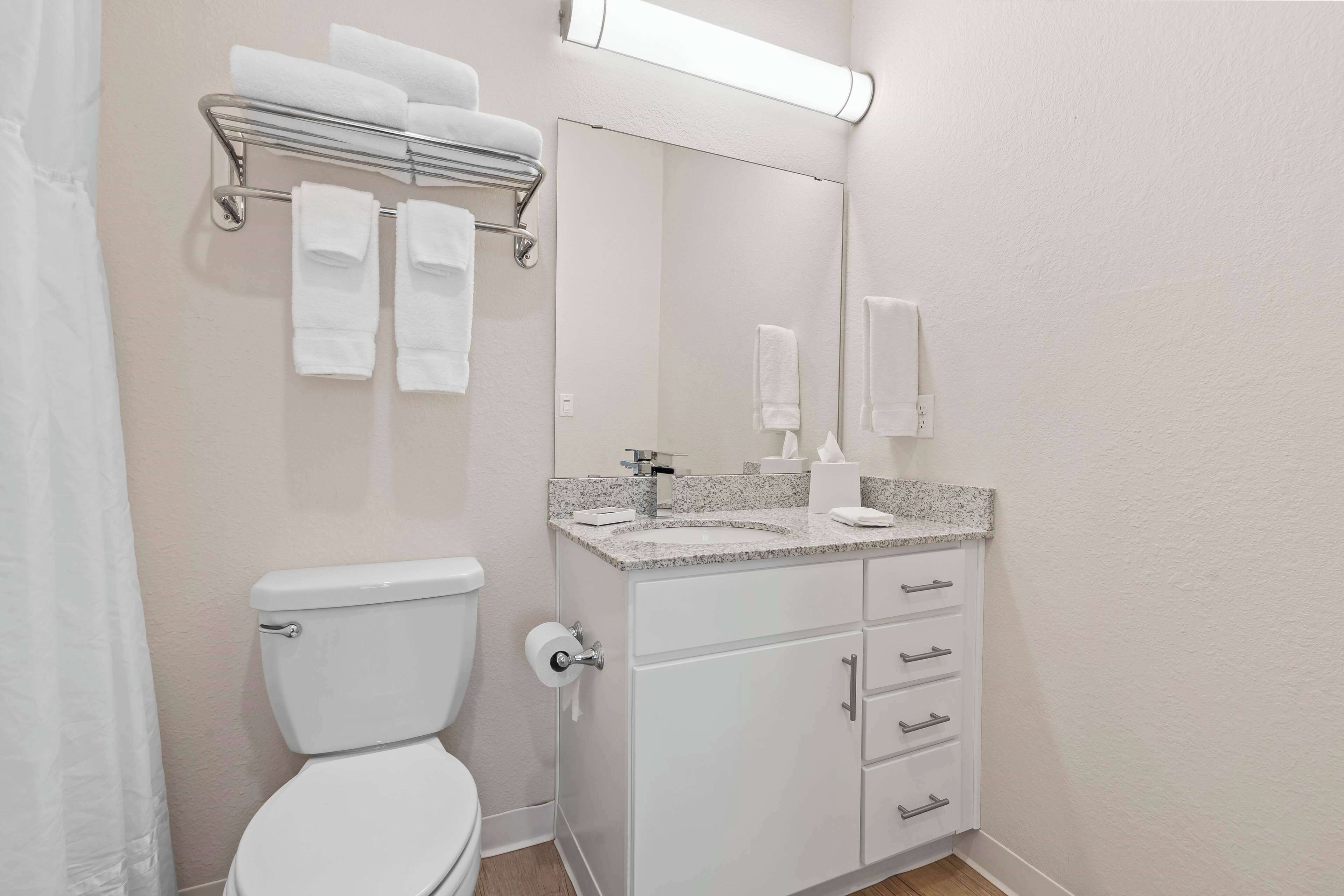 Een badkamer met toilet, wastafel, badkamermeubel, handdoekrek en spiegel.
