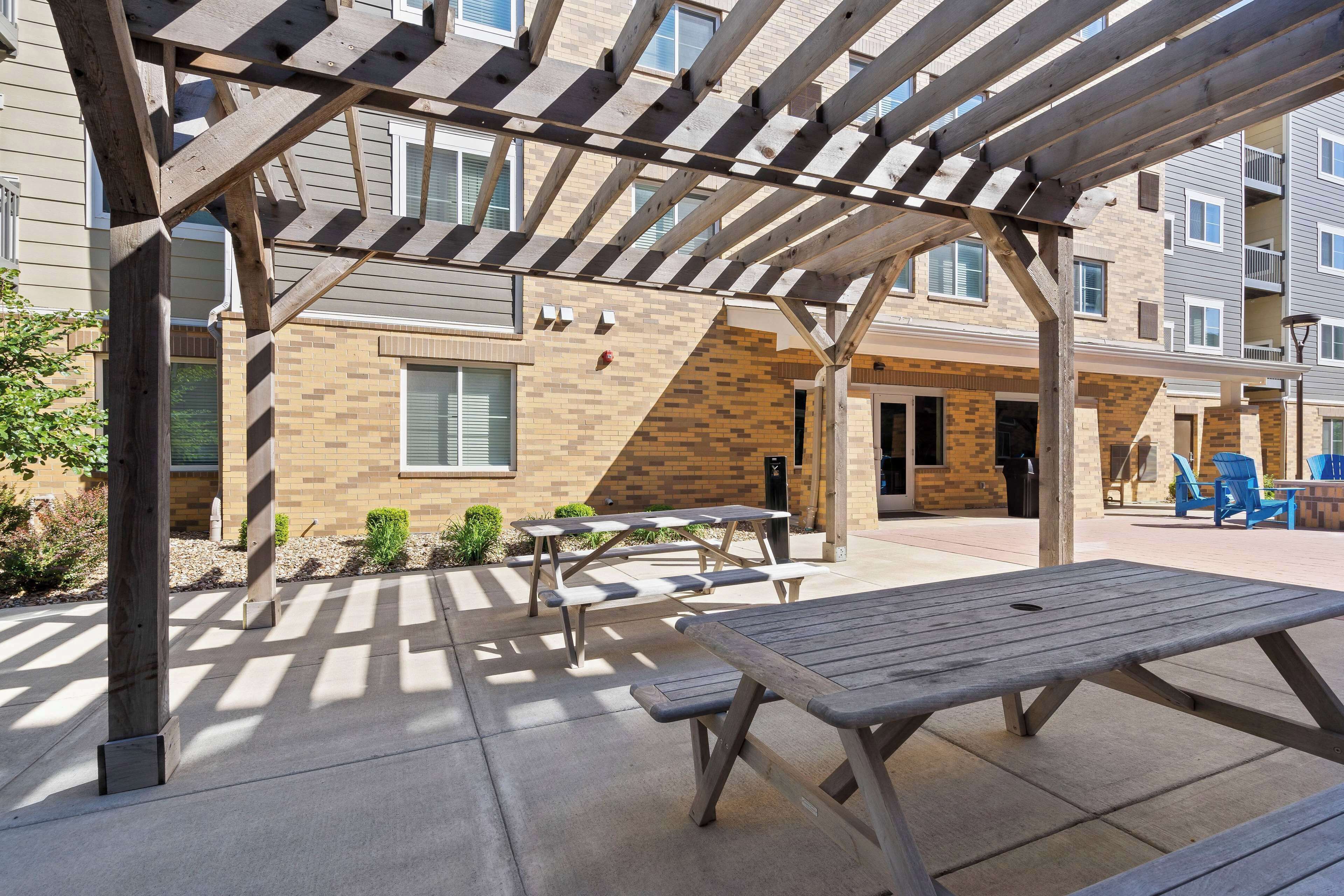 An outdoor patio area with picnic tables and a pergola structure.