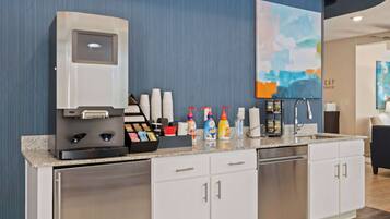 A modern kitchen with a coffee machine, tea station, and various condiments.