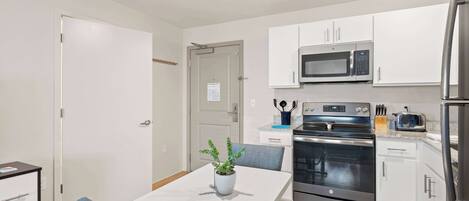 A modern kitchen with white cabinets, stainless steel appliances, and a dining area with a table and chairs.