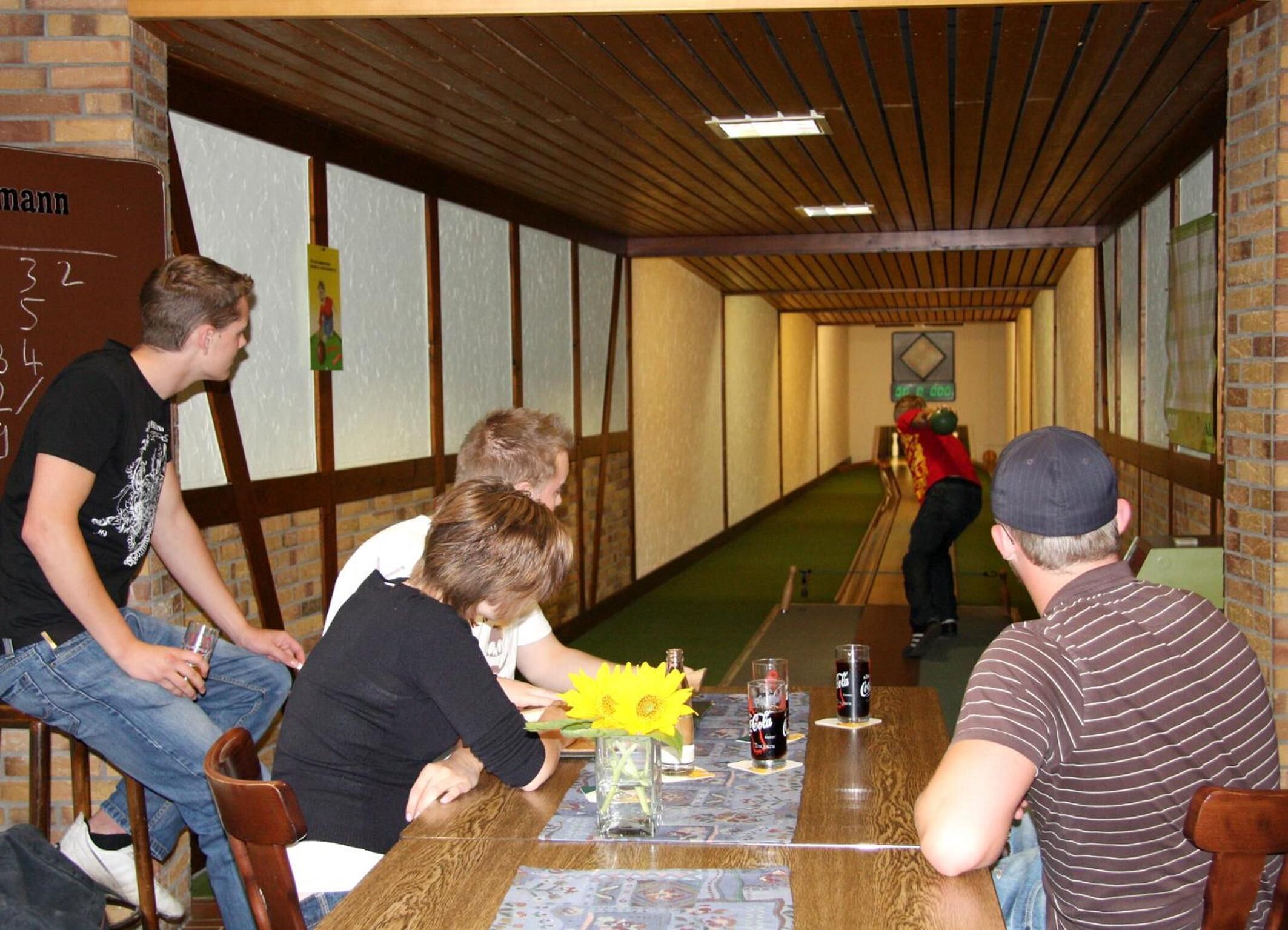 Uma pista de boliche com paredes de madeira e carpete verde.