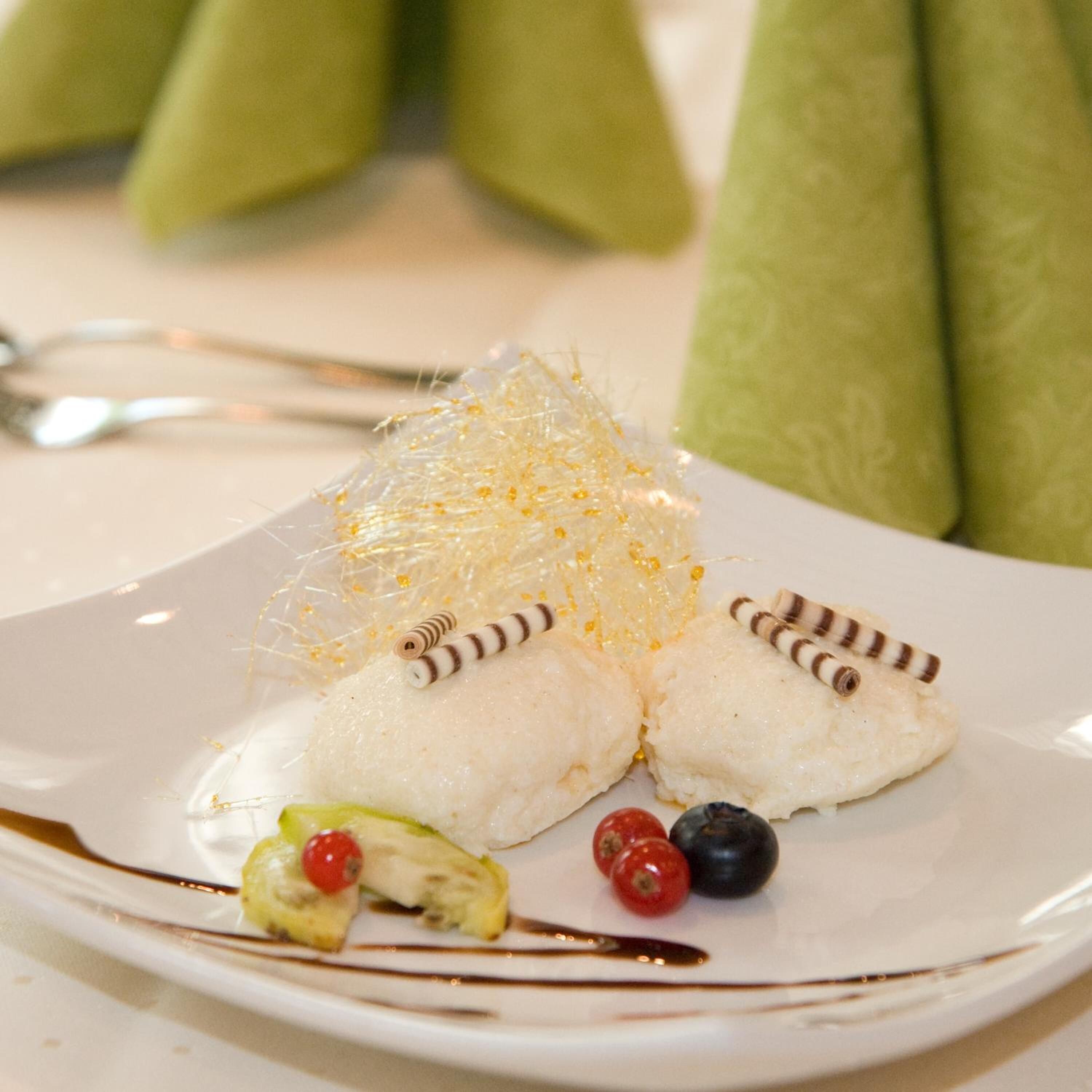 A dessert plate with white cake, a decorative sugar nest, and berries.