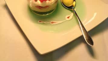 Un postre en un bol de vidrio sobre un plato cuadrado, con una cuchara a un lado.
