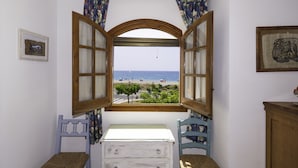A room with a large arched window offering a view of the beach and sea.