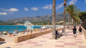 A beach with palm trees, a pool, and a view of mountains.