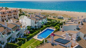 A resort with a swimming pool, beach access, and Mediterranean-style architecture.