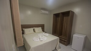 A hotel room with a bed, a wardrobe, and a small refrigerator.