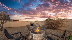 Patio con una chimenea, mobiliario exterior y vista al cielo.