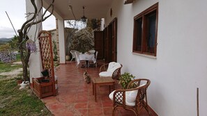 A covered patio with a table and chairs, a wooden fence, and a view of the landscape. - Sun House (Calatafimi Segesta)