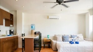 A compact room with a kitchenette, a bed, a ceiling fan, and a water dispenser. - Casa Mango Suite 3, Isla Mujeres. (Isla Mujeres)