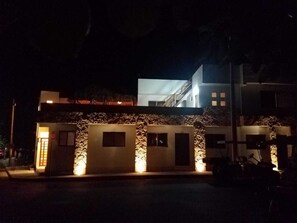 Un bâtiment moderne avec une façade en pierre, de nombreuses fenêtres et une entrée illuminée.