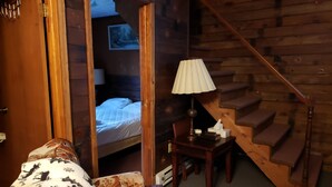 Een gezellige kamer met een bed, een stoel, een lamp en een trap.