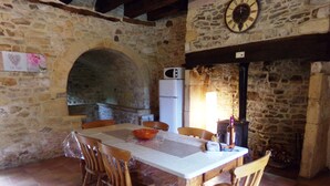 A rustic stone interior with a stone archway, a wooden table with chairs, a clock, and a fireplace. - Near Sarlat and Rocamadour, heated swimming pool  (Nadaillac-de-Rouge)