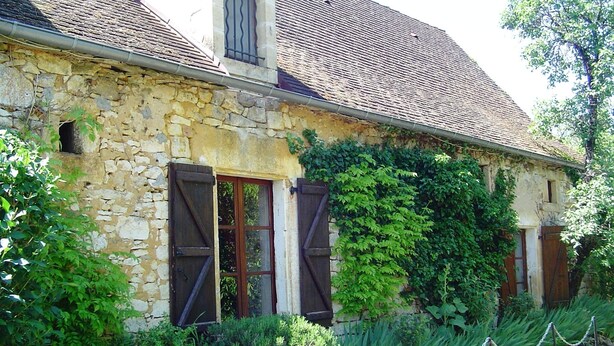 A rustic stone building with a sloped roof, wooden shutters, and a chain-link fence in front. - Near Sarlat and Rocamadour, heated swimming pool  (Nadaillac-de-Rouge)