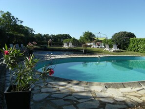A swimming pool with a stone border, surrounded by white lounge chairs and a grassy area with trees. - Near Sarlat and Rocamadour, heated swimming pool  (Nadaillac-de-Rouge)