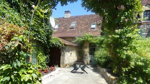 A courtyard with a stone building, a satellite dish, and a table with chairs. - Near Sarlat and Rocamadour, heated swimming pool  (Nadaillac-de-Rouge)