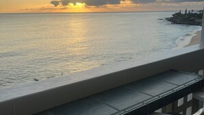Blick auf das Meer vom Balkon mit Tisch und Stühlen, mit Blick auf den Ozean und eine entfernte Küstenlinie mit Gebäuden.