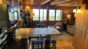 A cozy cabin interior with a kitchen, dining area, and seating space.