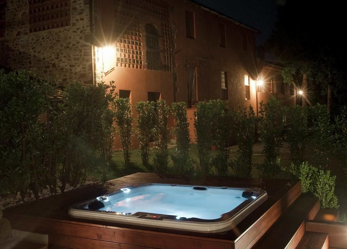 Un bain à remous dans un jardin, avec un bâtiment en pierre en arrière-plan.