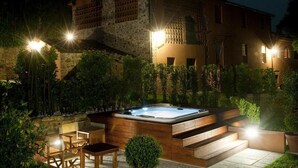 Un edificio de piedra con jacuzzi y mobiliario de exterior.