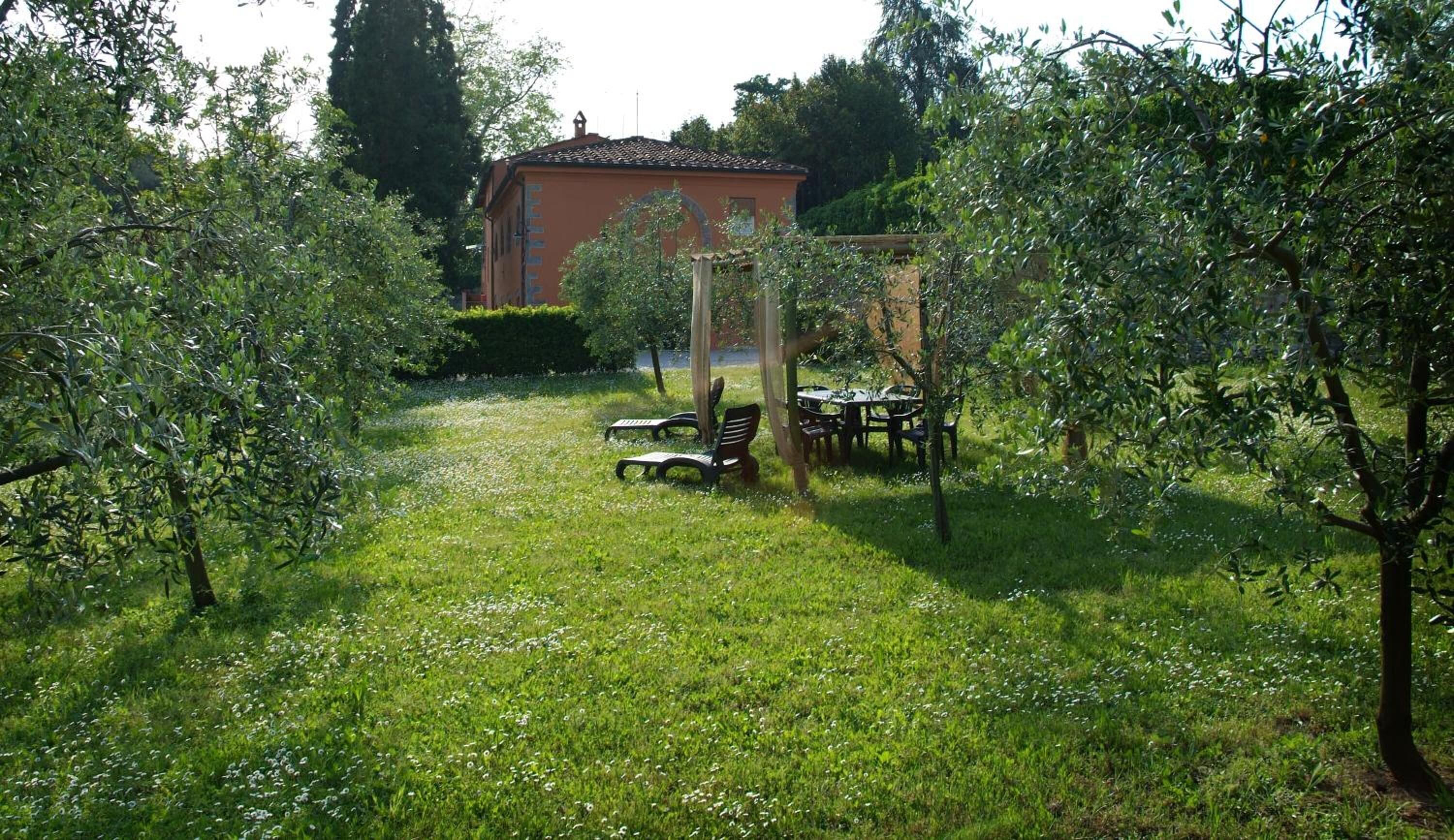 A garden with a pergola, outdoor seating, and a building in the background.