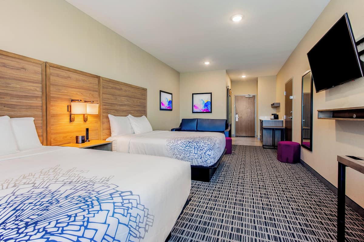 Une chambre d’hôtel avec deux lits, une télévision, un bureau et une salle de bain.