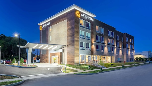 A multi-story hotel with a modern design, featuring a prominent entrance with a covered walkway and a well-lit facade.