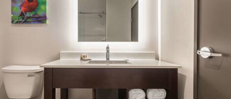 Un baño moderno con un lavabo blanco, un mueble oscuro y un box de ducha de vidrio.