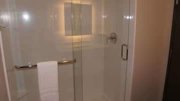 A glass-enclosed shower with a towel rack and a small mirror.