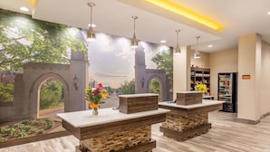 A lobby with reception desks, a mural of a cityscape, and a bookshelf with magazines.