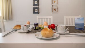 A breakfast table with plates, eggs, a croissant, and a coffee cup. - Timeless and elegant: the semi-detached house impresses with both its brightness (Carolinensiel)